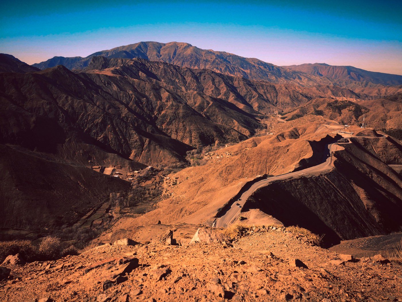 The High Atlas, a road winding down through red ridges to villages on the valley floor