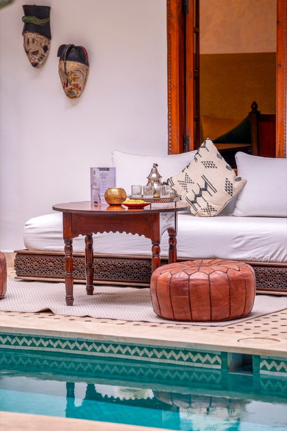 A daybed set with a silver tea service beside the zellige edge of the pool