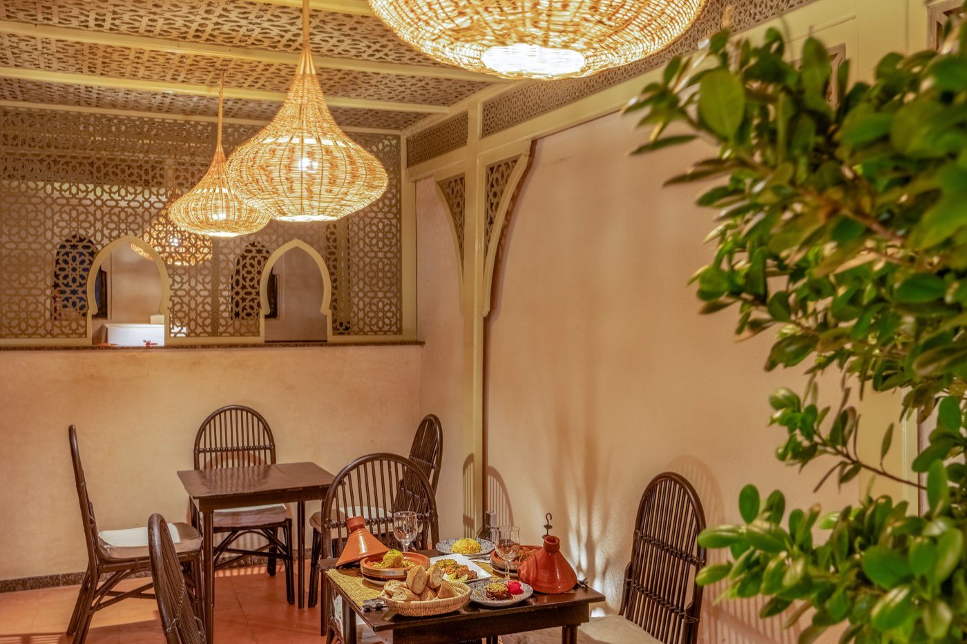 The covered corner of the roof terrace, its carved ceiling and arched screens above tables set for the evening
